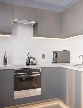 Modern gray kitchen with white tile backsplash, stainless oven, sink, kettle, and toaster on the counter