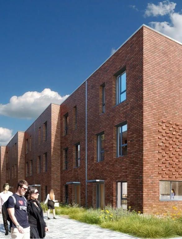 People walking beside a modern brick building under a blue sky