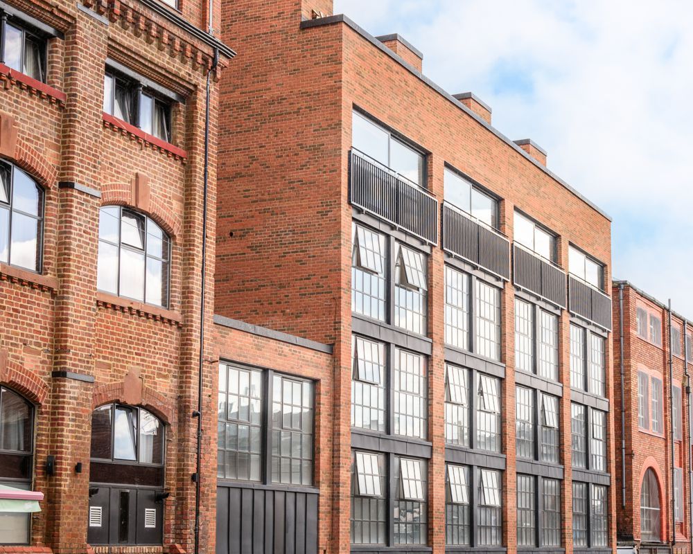 Red brick row of industrial-style buildings with large windows on a city street