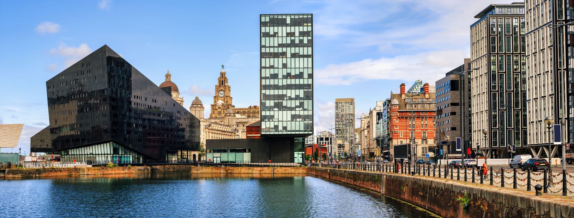 Canal waterfront with modern and historic buildings under a blue sky
