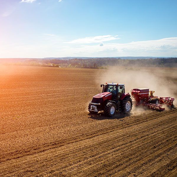 An aerial view of a tractor plowing a field at sunset.