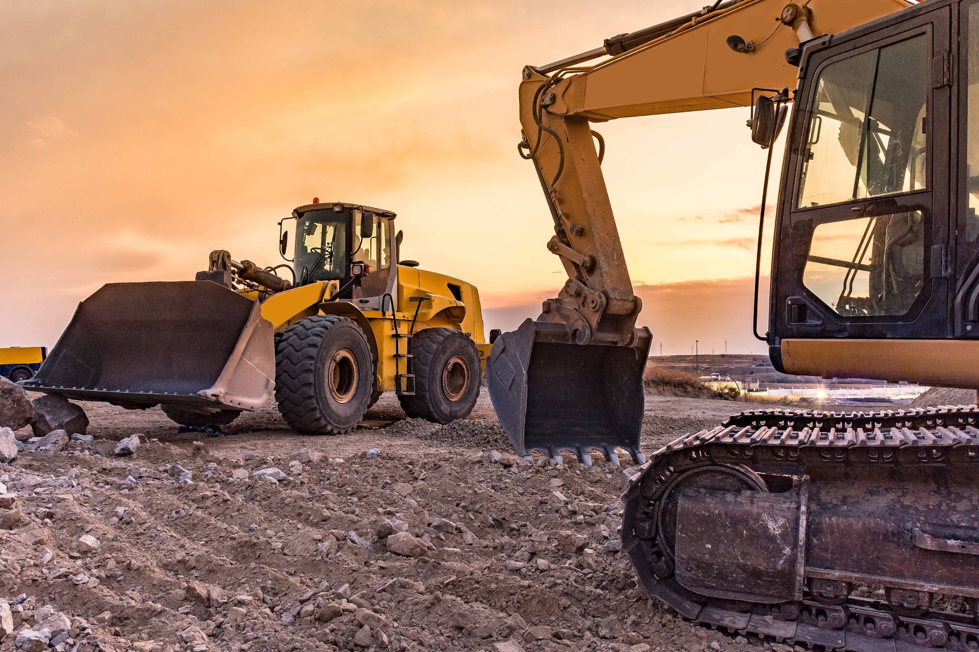 Yellow construction equipment on a construction site at sunset.