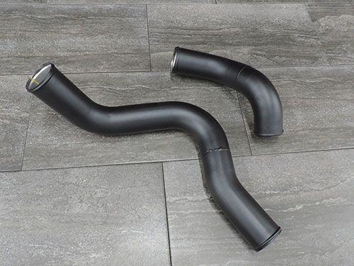 Two black hose pipes are sitting on a tiled floor.