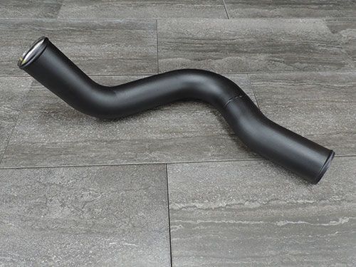 A black pipe is sitting on a tiled floor.