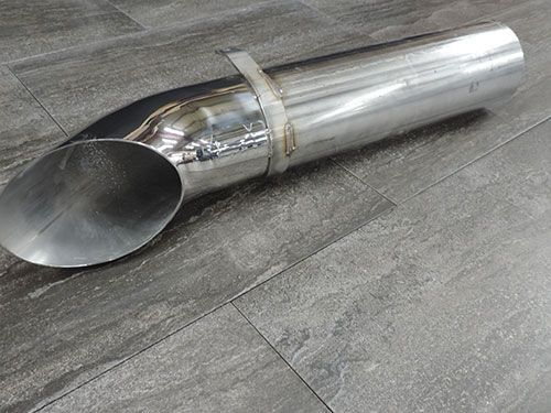 A stainless steel pipe is laying on a tiled floor.