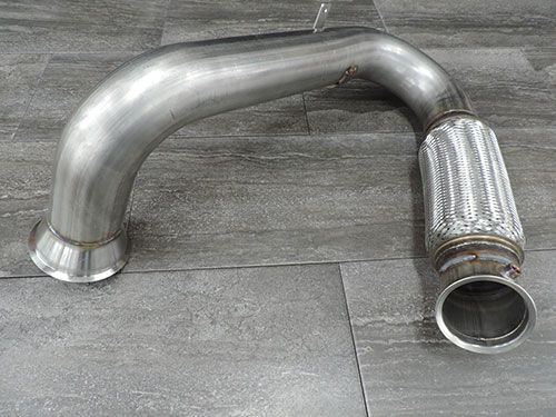 A stainless steel pipe is sitting on a tiled floor.