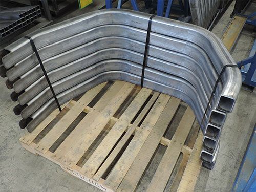 A bunch of metal pipes are stacked on top of each other on a wooden pallet.