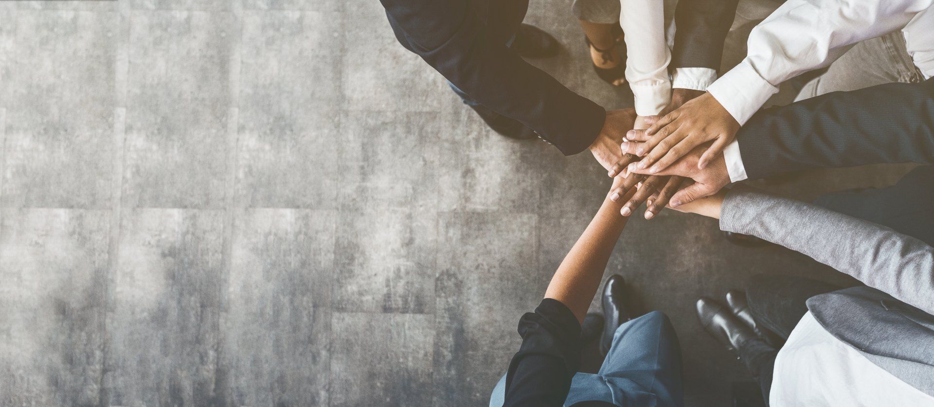 A group of people are putting their hands together in a circle.