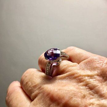 A woman is wearing a ring with a purple stone on her finger.