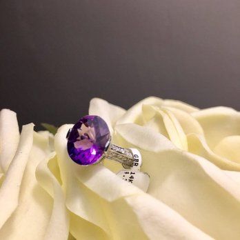 A purple ring is sitting on top of a white rose
