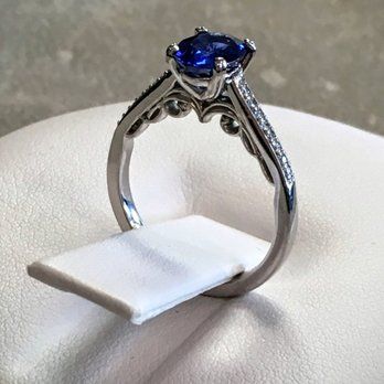 A sapphire and diamond ring is sitting on a white cloth.
