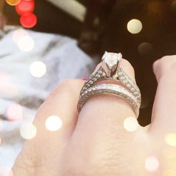 A woman is wearing a wedding ring and an engagement ring on her finger.