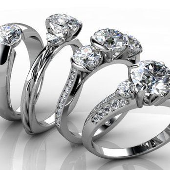 Three rings with diamonds on them are lined up on a white surface.