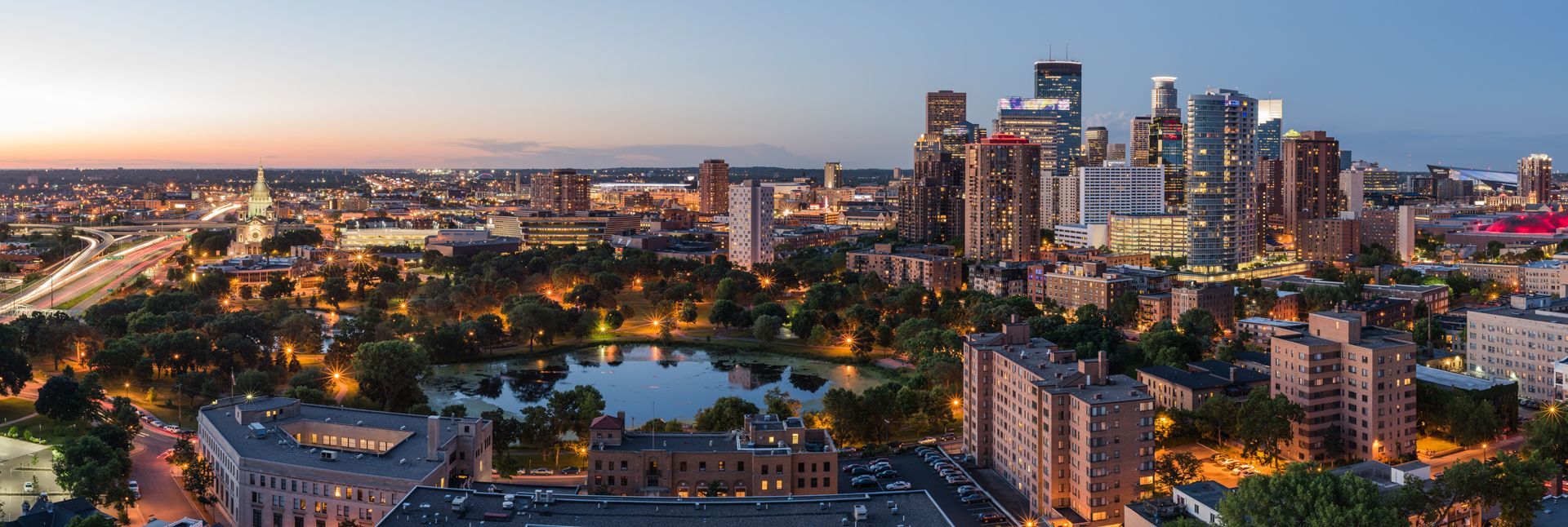 An aerial view of a city at night with a lake in the middle of the city.