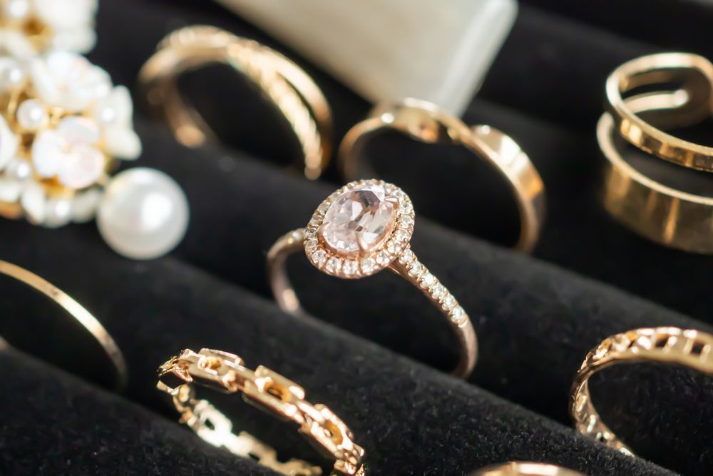 A variety of gold rings are sitting on a black velvet tray.