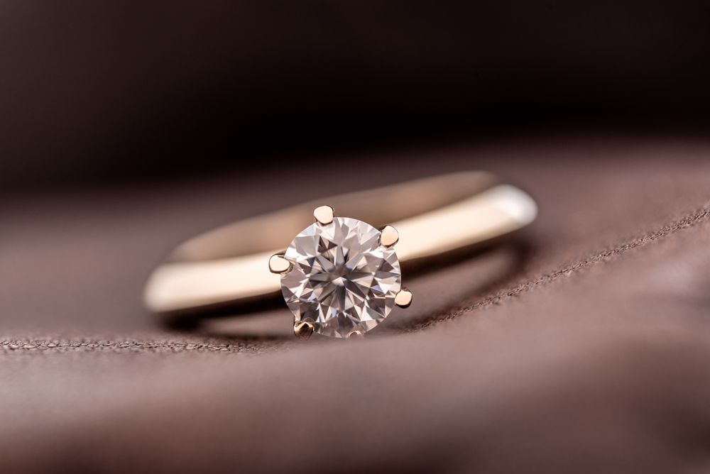 A close up of a diamond ring on a brown cloth.