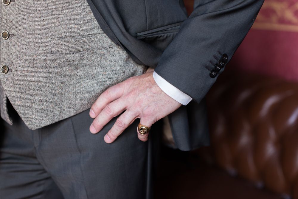 A man in a suit and vest is standing with his hand on his hip.