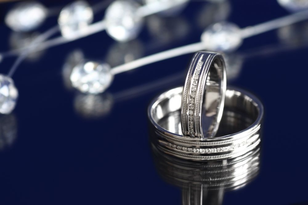 A pair of wedding rings are sitting on a blue surface.