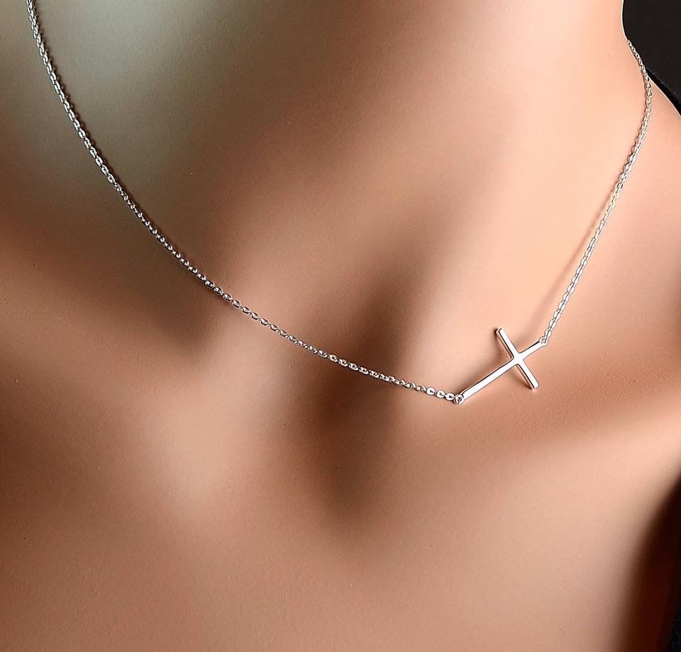 A woman is wearing a necklace with a cross on it