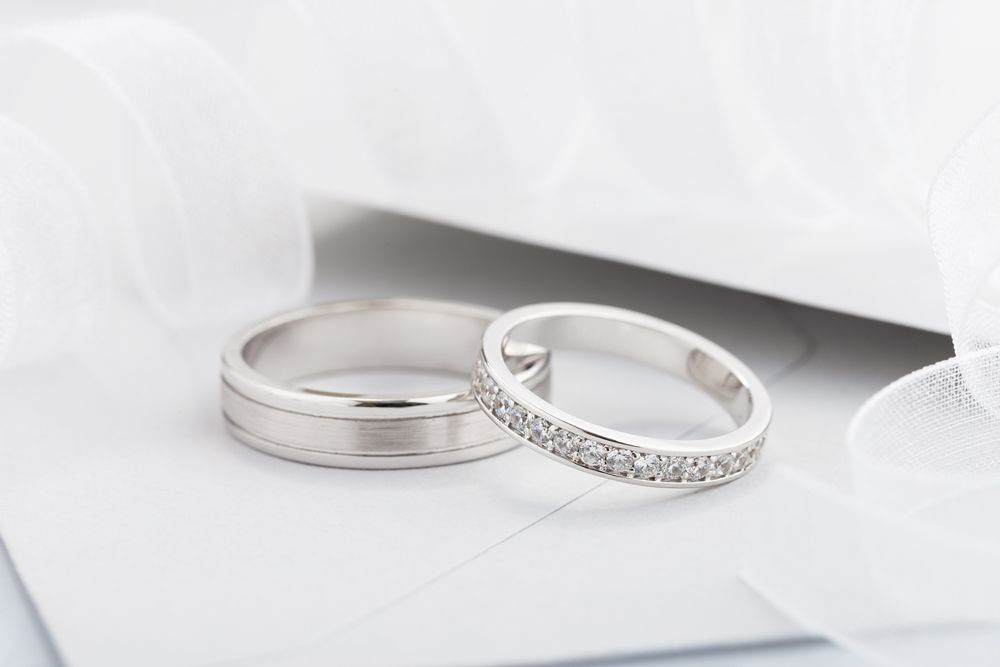 A pair of wedding rings are sitting on top of a white envelope.