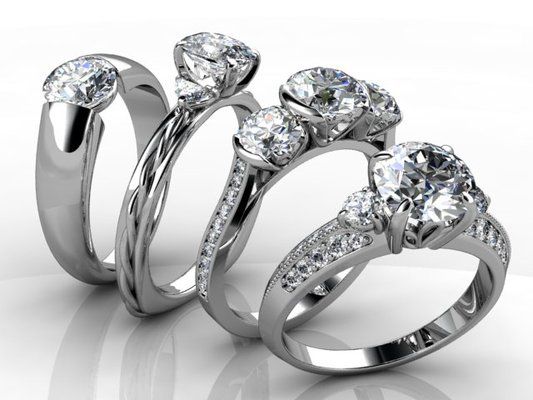 Three rings with diamonds are lined up on a white surface