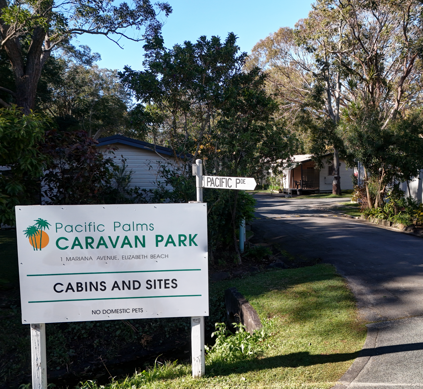 A bedroom with a bed , nightstand , and bathroom — Pacific Palms Caravan Park in Elizabeth Beach, NSW