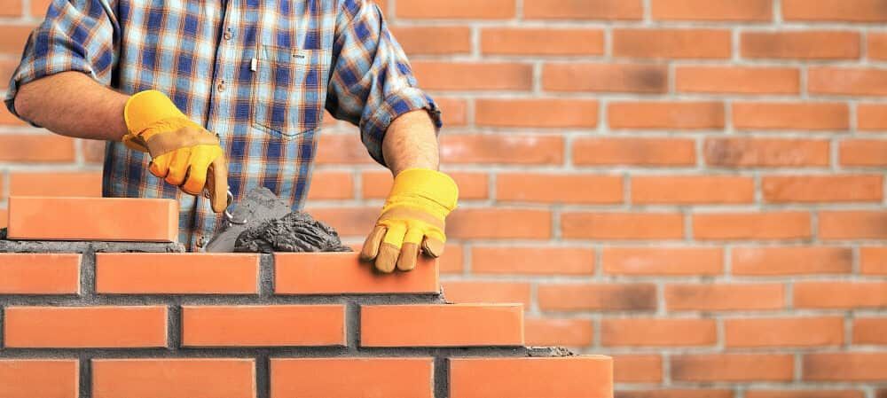 A Man Is Laying Bricks On A Brick Wall — Mascrete Pty Ltd In Hermit Park, QLD