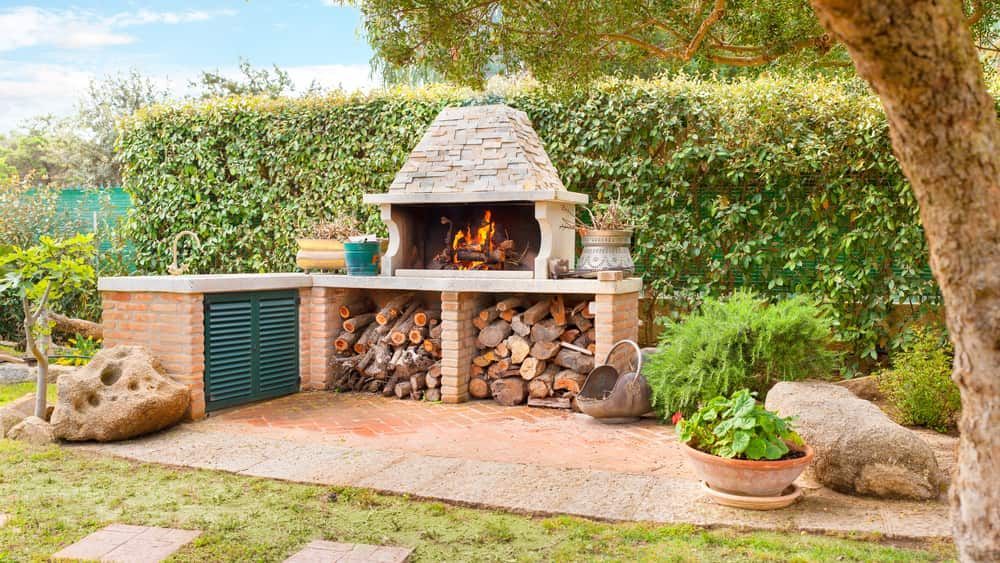 A Barbecue Grill Is Sitting In The Middle Of A Garden Next To A Pile Of Logs — Mascrete Pty Ltd In Hermit Park, QLD