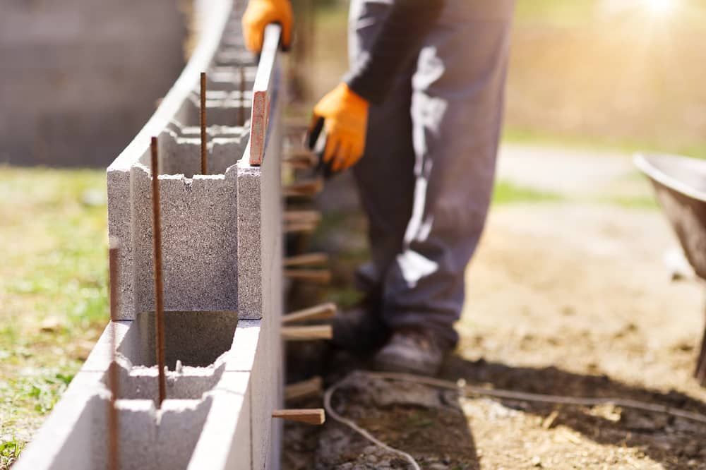 A Man Is Laying Concrete On A Brick Wall — Mascrete Pty Ltd In Hermit Park, QLD