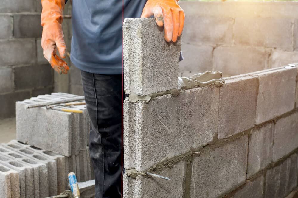 A Man Is Building A Brick Wall On A Construction Site — Mascrete Pty Ltd In Hermit Park, QLD