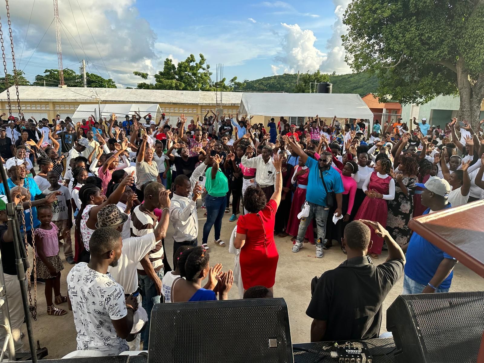 A large group of people are dancing in front of a dj.