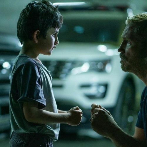 A man is talking to a young boy in a parking garage.