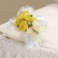 Yellow flower bouquet on a white pillow with sheer ribbon and lace trim