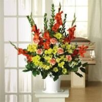 Colorful mixed flower arrangement in a white vase on a pedestal by a bright window