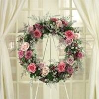 Floral wreath of pink and white roses hanging on a window with sheer curtains