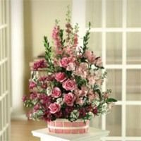 Pink rose bouquet in a basket on a white table by a window