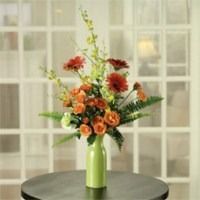Mixed flower bouquet in a lime-green vase on a round black table, with a windowed backdrop