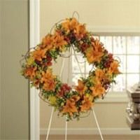 Autumn leaf wreath with orange and yellow flowers on a white easel indoors