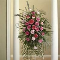 Standing floral arrangement with pink roses and greenery on a white stand