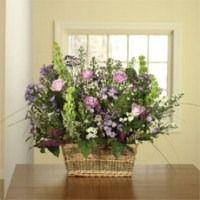 Basket of purple and white flowers on a wooden table in front of a window