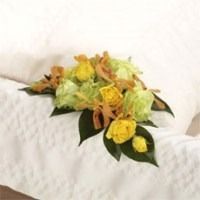 Yellow and green floral arrangement on a white quilted bedspread
