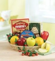 Basket of apples and cherries with a red fruit snack box and sliced green apple on a bright table.