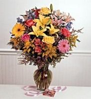 Colorful mixed bouquet of flowers in a vase on a table with scattered petals