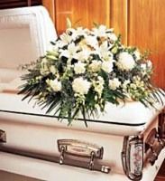 White casket topped with a bouquet of white flowers at a funeral setting