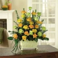Yellow and green flower bouquet in a white vase on a wooden table by a sunlit window