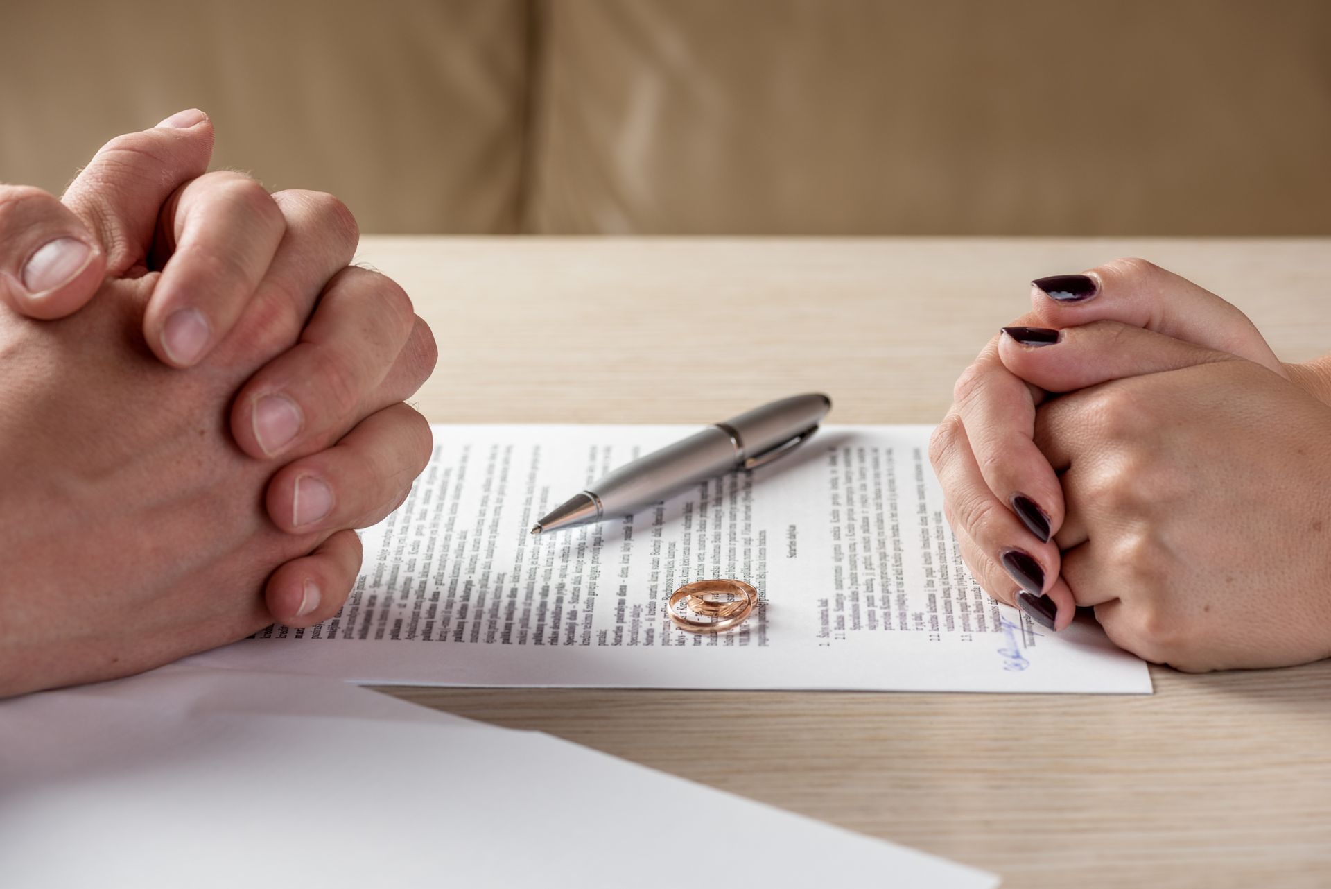 Hands clasped across a signed document with a pen on a table
