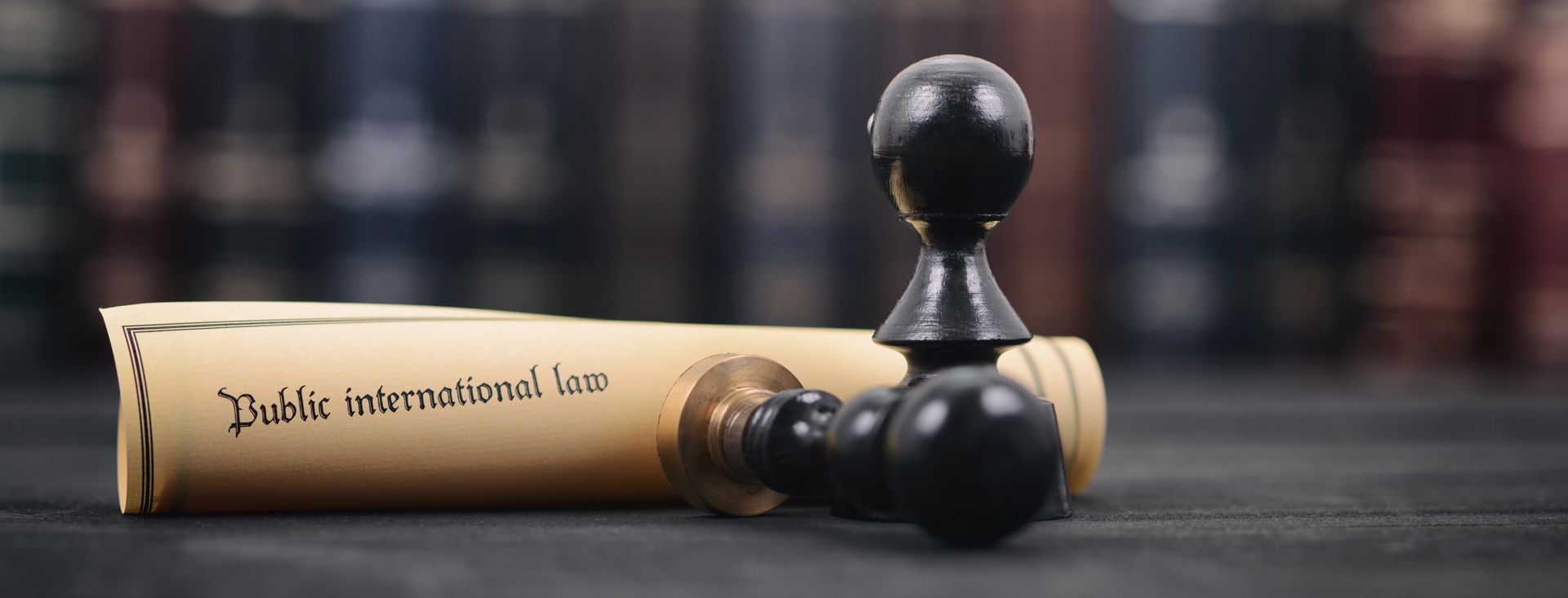 Wooden gavel resting on a black chess king and pawns on a dark table