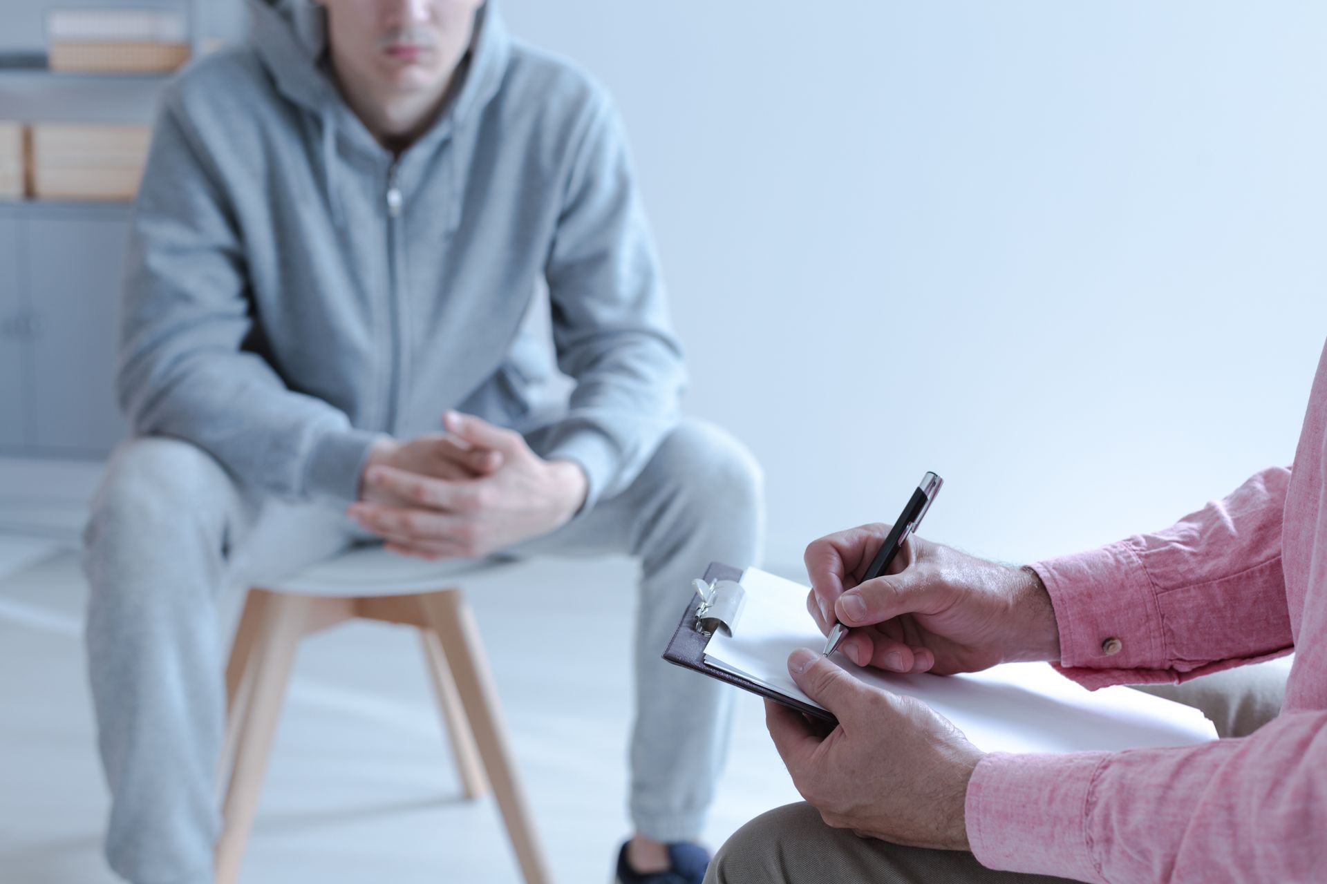 Counselor taking notes while speaking with a seated client in a bright office