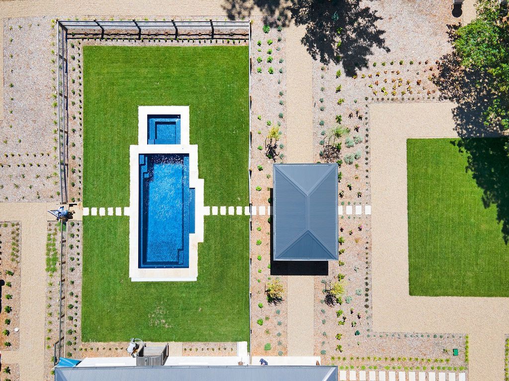 Aerial view of a courtyard with a central swimming pool, green lawns, and paved walkways.
