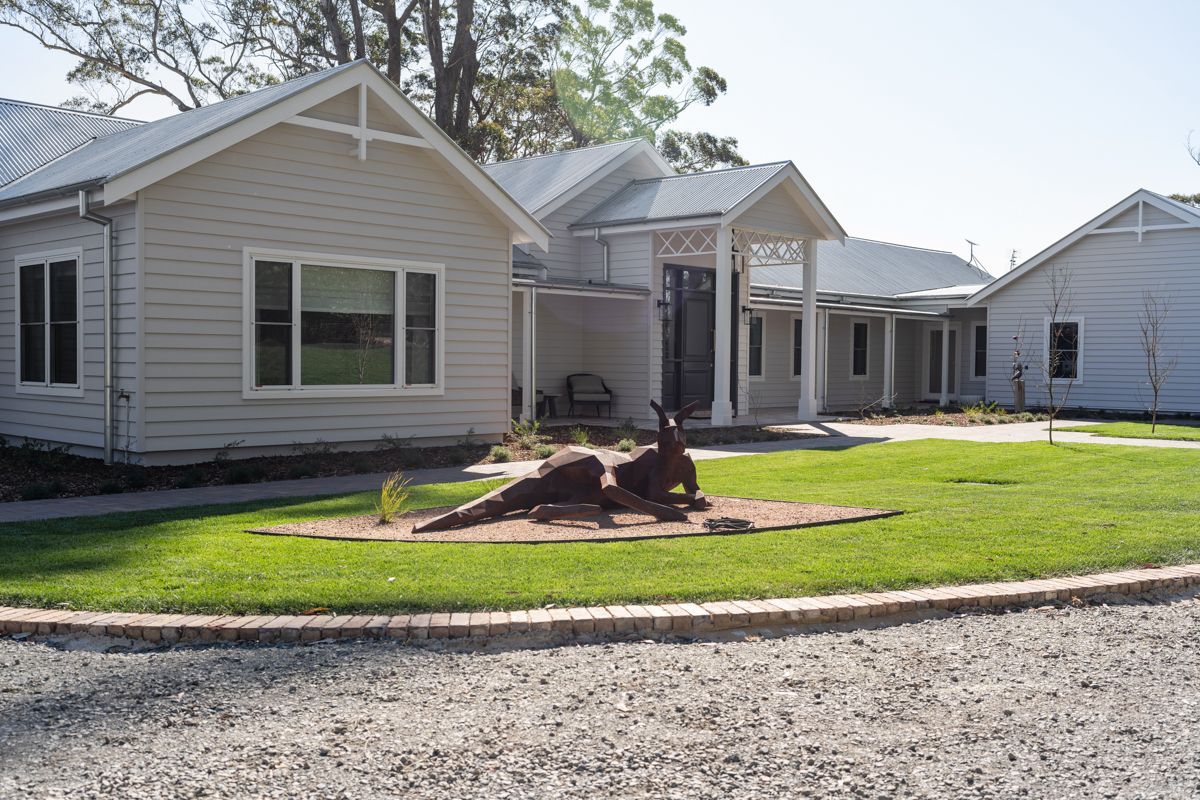 Row of light-gray houses with green lawns and a gravel driveway under sunny skies